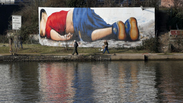 Un grafitti que emula la fotografa de Aylan en la playa frente al ro Main en Frankfurt. / Michael Probst - AP Photo