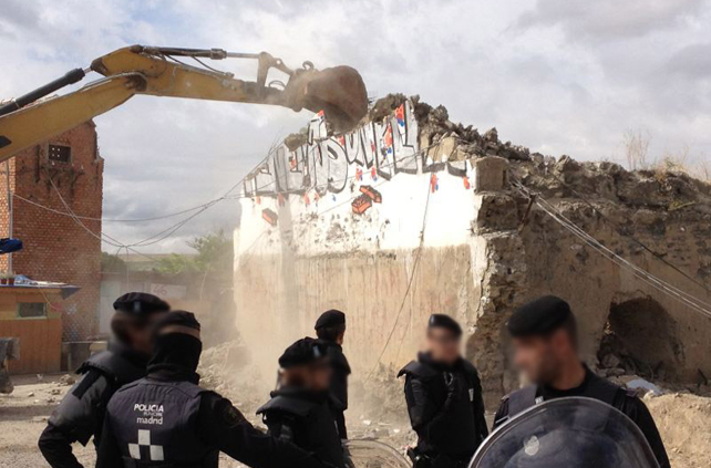 Una mquina excavadora derriba una vivienda en el poblado de El Gallinero bajo la mirada de varios policas municipales.